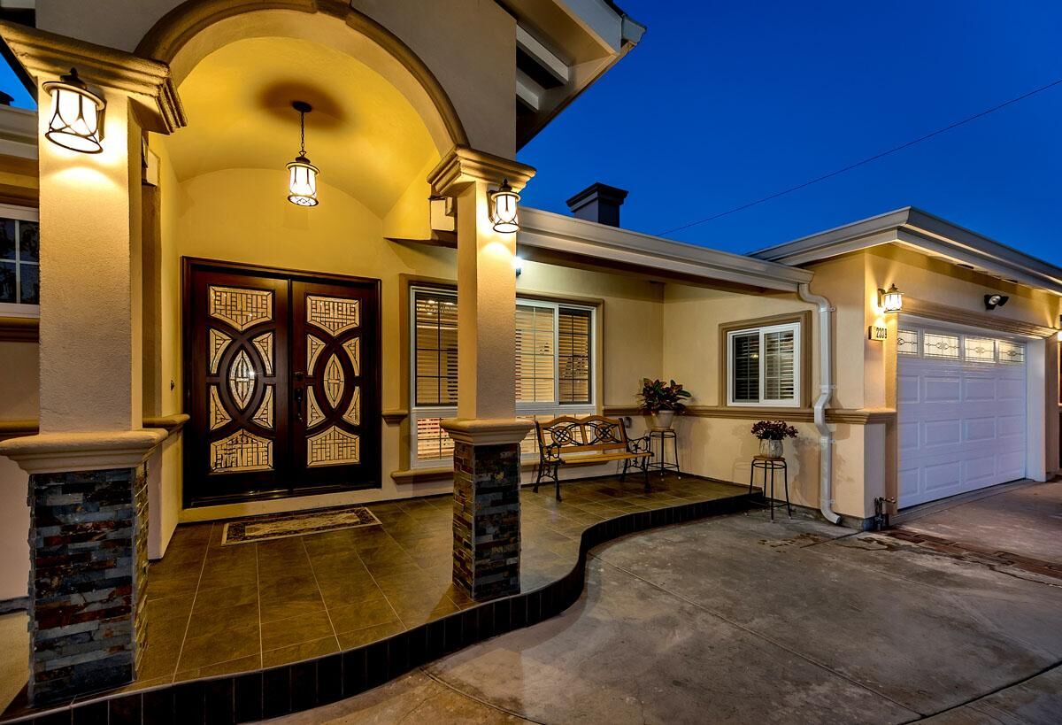 Covered front entry porch with stone columns lit at twilight