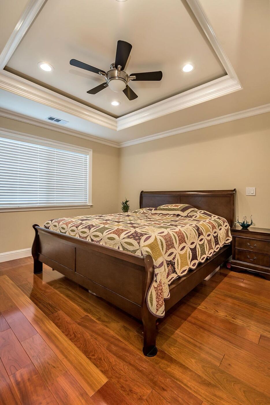 Master bedroom with custom tray ceiling and hardwood floors